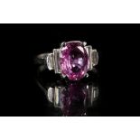 A platinum, pink sapphire and diamond ring, the oval cut sapphire flanked by baguette cut diamond