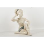 A French porcelain figure of a nude girl kneeling with enamelled drape and headband.