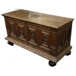 A 19th century oak coffer with floral carved front panels, raised on large bun feet, 145 x 58cm.