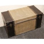 A black painted trunk with hinged lid revealing storage space, clad with sea grass.