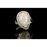 An 18ct white gold, cabouchon opal and diamond set dress ring. Opal: 16 x 11mm. Diamonds: 0.60ct