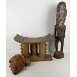 An Ashanti stool, together with a Chokwe mask and a Sepik river figure.