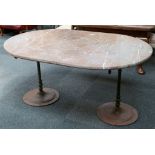 A large oval Sienna marble topped garden table, with twin iron scroll supported arms on vertical