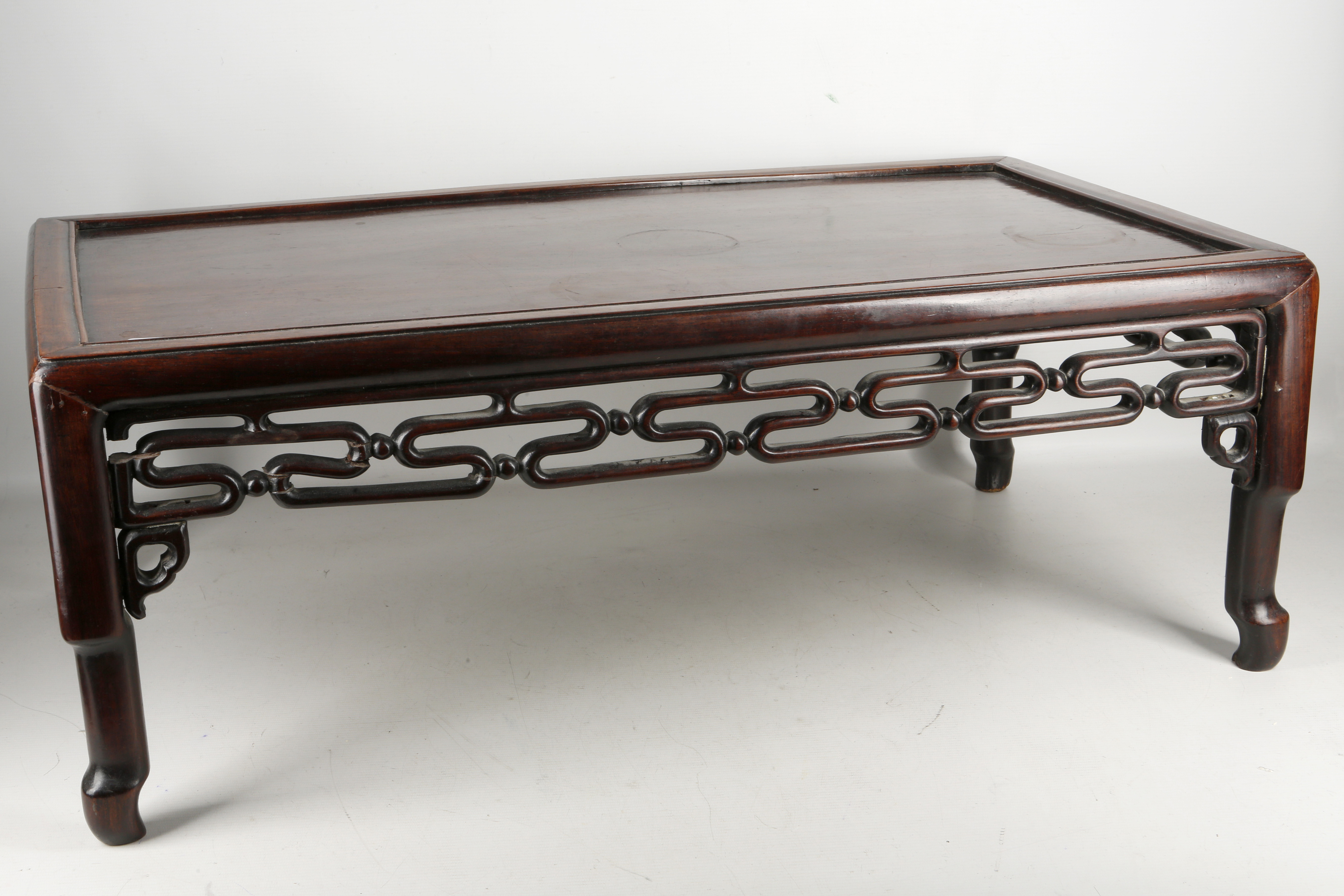 A Chinese wooden low table, well patinated with carved and pierced geometric arrows, early mid
