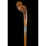A FOLK ART WALKING CANE. With a carved wooden cari
