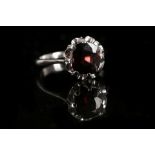 A white metal and red spinel ring, set cushion cut single stone within a claw mount, bears