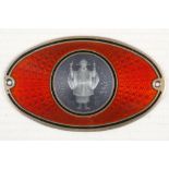 A small oval metal plaque, depicting an engine turned enamelled oriental gentleman, surrounded by