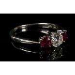 An 18 carat white gold, diamond, and ruby three stone ring, set central round cut diamond of approx.
