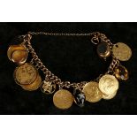 A 9 carat yellow gold flat curb link bracelet, hung with various yellow metal coins and charms, to