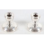 A pair of hallmarked silver ladies dwarf miniature table candlesticks, raised on circular bases,