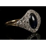 A yellow gold, diamond, and sapphire cluster ring, set oval cabouchon cut sapphire, the mount pave