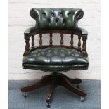 A green and button upholstered rocking and swivelling desk captain's chair on five legs.