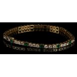 An 18 carat yellow gold, diamond, and emerald set articulated line bracelet, the diamonds of approx.