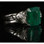 A platinum, emerald, and diamond ring, set emerald cut central stone of approx. 3.64 carats, flanked