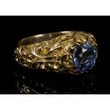 A yellow metal and Ceylon blue sapphire ring, set round cut stone within a a naturalistic stylised