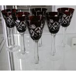 A set of six Bohemian cranberry glass overlay wine glasses, each with a cut bowl raised on a plain