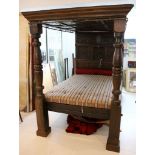 A four poster bed in Elizabethan style, with carved headboard and chunky turned column supports,