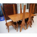 A teak dining table and 6 high back chairs of Arts & Crafts style, bird carving to backs, table