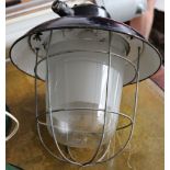 A pair of black enamelled industrial storm lanterns with protective cages, overall diameter 34cm,