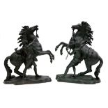 A pair of traditional bronze Marley horses with attendants on naturalistic bases.