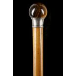 A TIGER'S EYE MALACCA DRESS CANE. The spherical tiger's eye knop rest on a spreading engraved silver