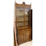 An Edwardian amboyna and walnut cross banded bookcase, with twin glazed doors over cupboard base,