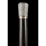 A CLOSE GRAINED ROSEWOOD AND SILVER CAPPED DRESS CANE. The grip of repousse and chased work has