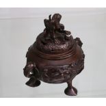 A 20th century Japanese bronze coro and cover, raised on  thee feet embossed with flora and fauna.