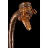 A FOLK ART CHERRY WALKING STICK. With grotesque caricature  portrait of a man with lolling tongue,