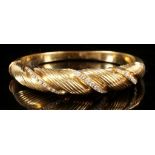 An 18 carat yellow gold and diamond bangle, of threaded twist design, set three rows of small