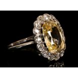 An 18 carat white gold, diamond, and pale yellow sapphire cluster ring, set oval cut sapphire of 5.7