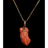 An unusual 18 carat yellow gold, diamond, and coral pendant, having coral carved in the face of a