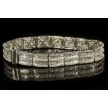 An 18 carat white gold and diamond articulated bracelet, set alternating lines of round and baguette