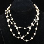 A triple strand pearl necklace, the pearls interspersed with white metal segments, having white