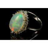 A white metal, diamond, and opal cluster ring, set oval cabouchon opal, surrounded by small