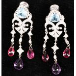 A pair of white metal, diamond, drop pendant screwback earrings, each having trillion cut aquamarine