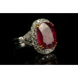 An 18 carat white gold, diamond, and ruby cluster ring, set oval cut ruby of approx. 6.20 carats,