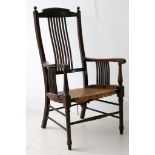 An Edwardian comb back elbow chair, comb supports to arms, rush seat, turned legs and stretchers.