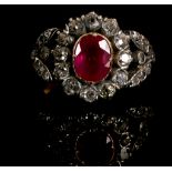 A yellow metal, diamond, and ruby cluster ring, set oval cut ruby of 1.4 carats, the mount and