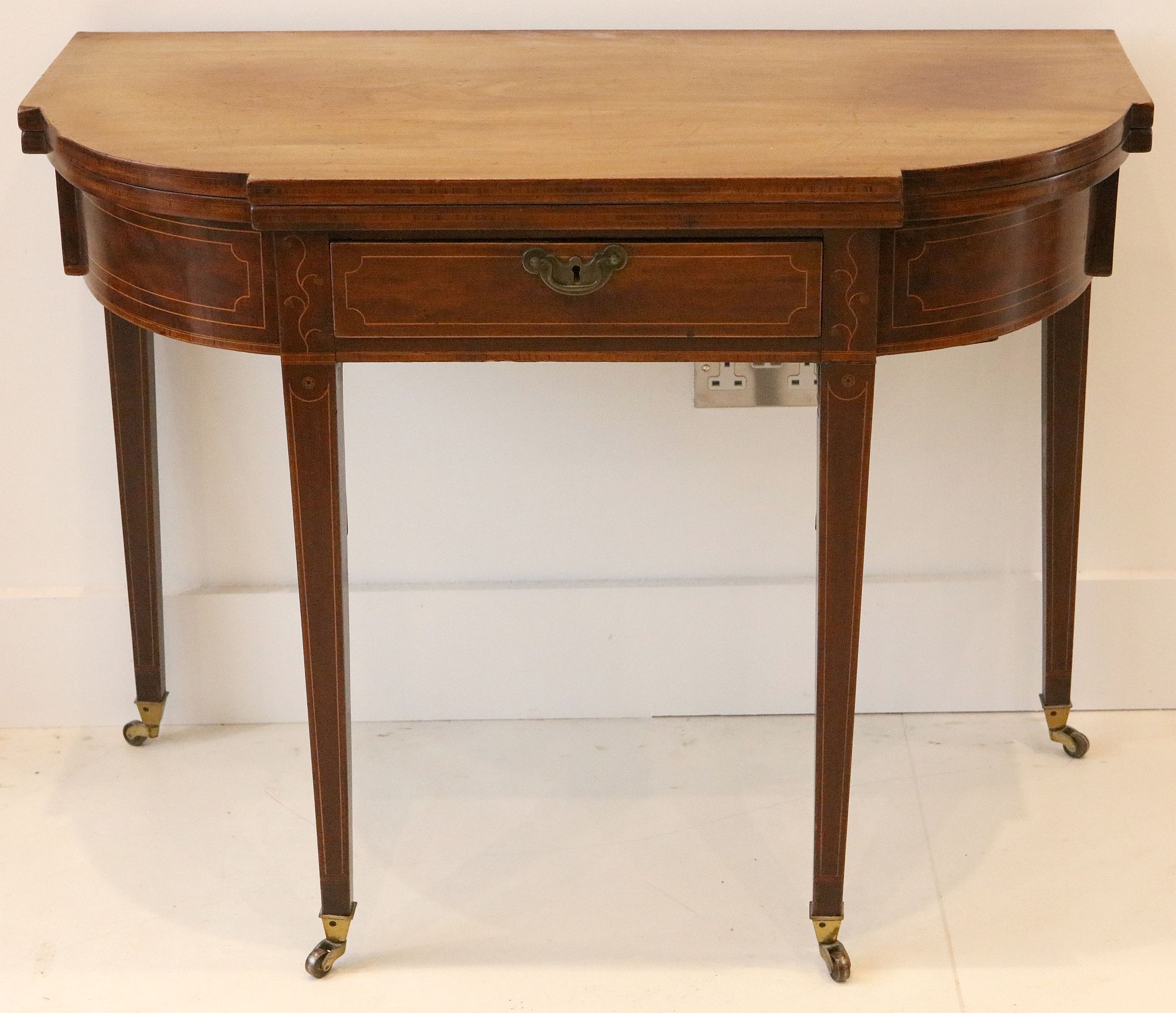 A George III mahogany card table, with shaped top and single drawer on square tapered legs and