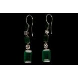 A pair of white metal, diamond, and emerald drop earrings, each set two round cut diamonds and three