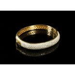 An 18 carat yellow gold and diamond bangle bracelet, pave set with numerous round cut diamonds.