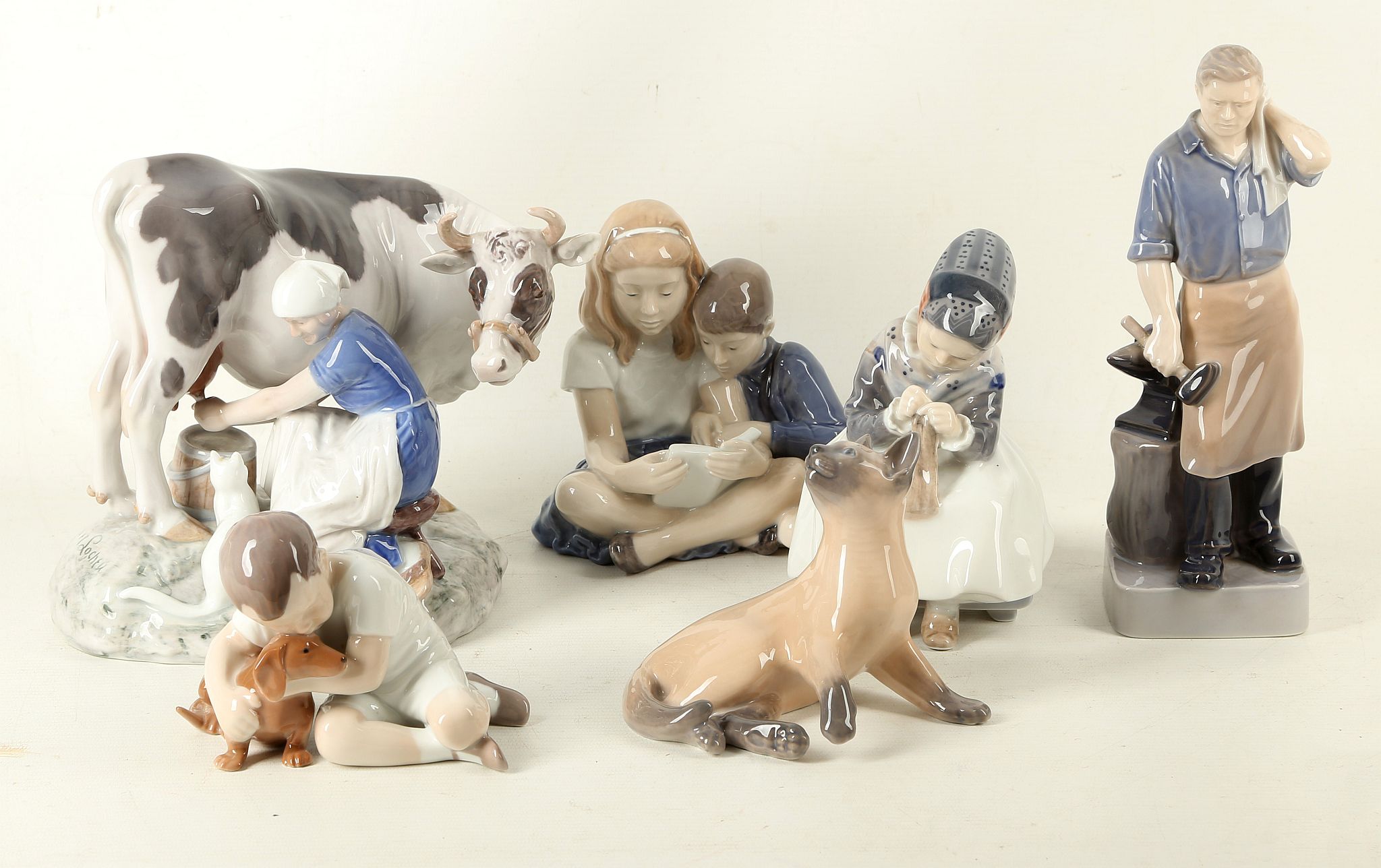A ROYAL COPENHAGEN PORCELAIN FIGURAL GROUP, modelled in the form of a milk maiden milking a cow,