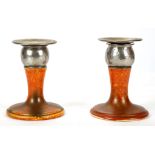 A PAIR OF EARLY 20TH CENTURY ROYAL LANCASTRIAN ORANGE GLAZED CANDLESTICKS, both having pewter