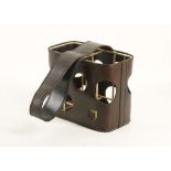 A 1950'S BROWN LEATHER AND BRASS BOTTLE HOLDER, with cut-out design, attributed to Jacques Adnet (