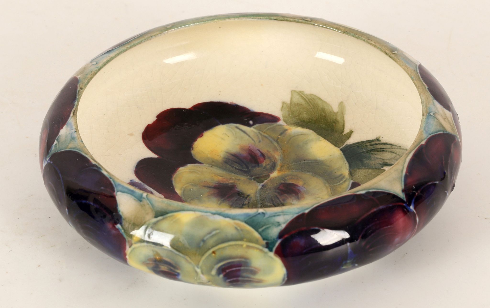 WILLIAM MOORCROFT 'PANSY' DISH, CIRCA 1920, with inverted rim, green painted signature under, (