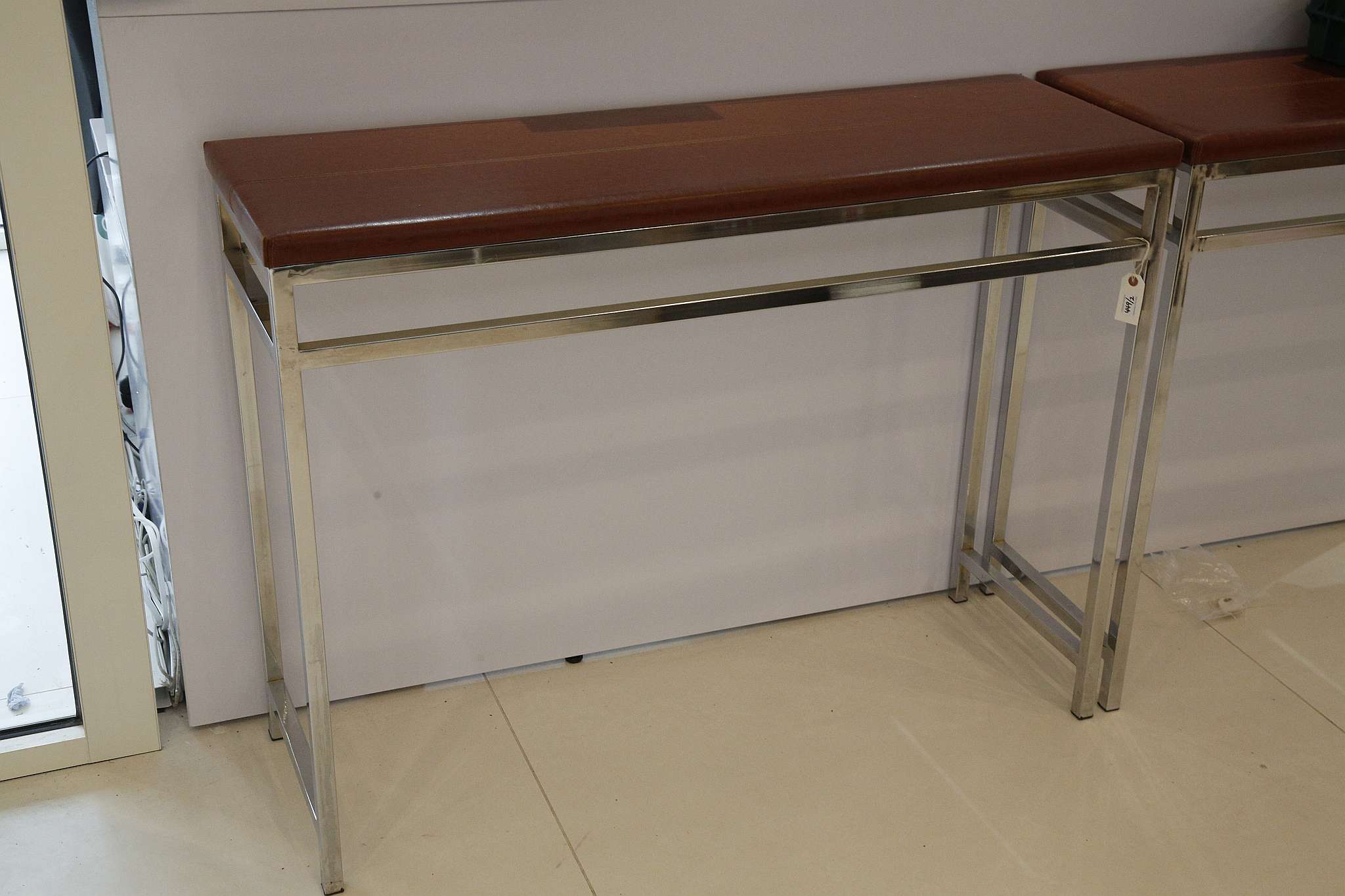 A pair of tan leather and polished steel hall tables, 91 x 120 x 40cm (2).