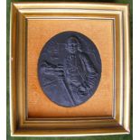 Black ceramic plaque depicting James Brindley, holding surveying instrument on tripod, with mill and