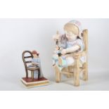 A 19th century Thuringian porcelain figure of a child sitting on a chair and spoon feeding her doll,
