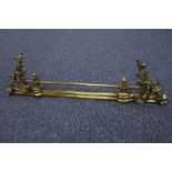 A French style brass fire rail with rococo swags at either end, sold with 3 fire irons.